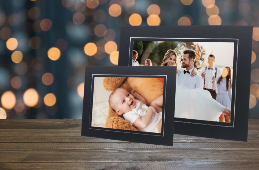 Two photo mounts on a table, one with a picture of a baby laying on a giant teddy bear, and the other of a groom carrying his bride.